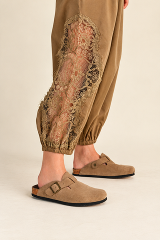 Women's camel balloon pants with floral lace inset detailing, elastic drawstring waistband, relaxed fit, and gathered ankle cuffs, styled with tan clogs.